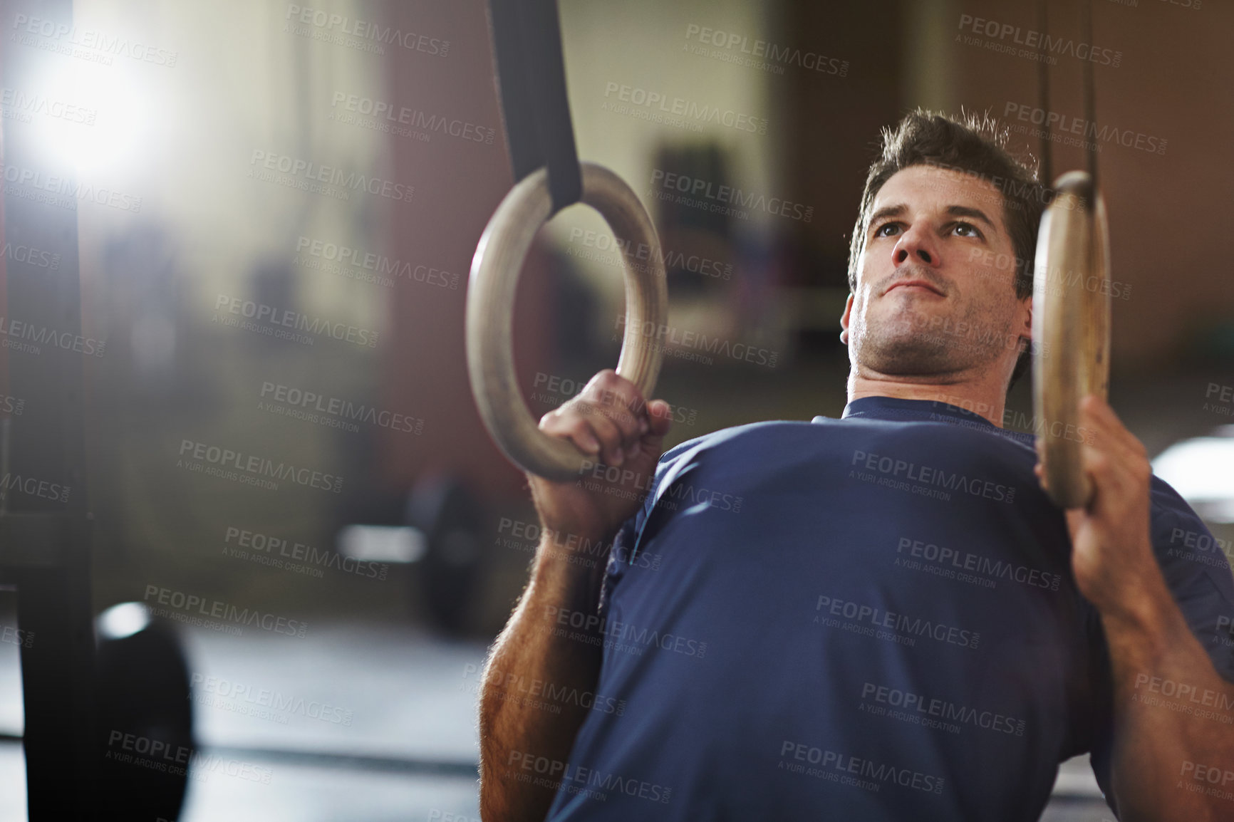 Buy stock photo Shot of a young man working out with gymnastics rings in a gym