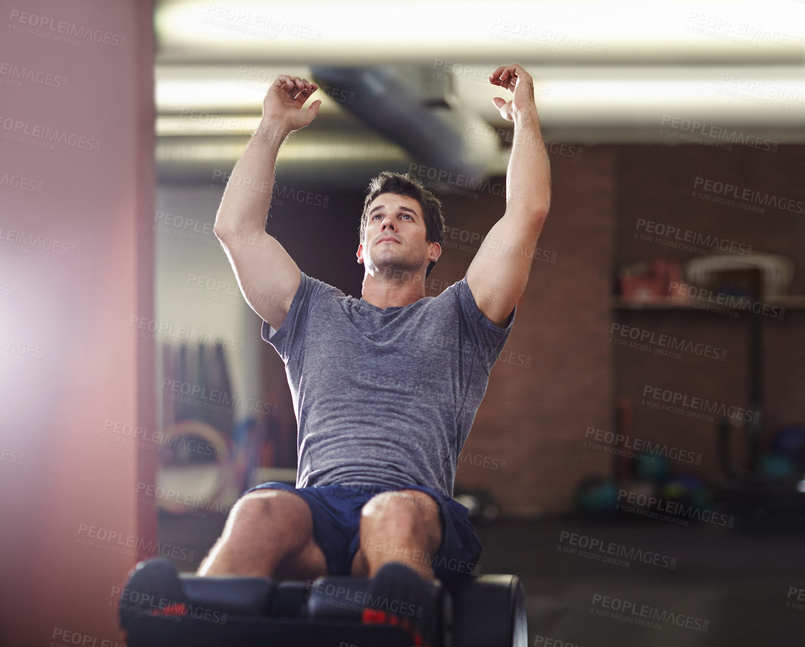 Buy stock photo Shot of a young man doing sit ups in a gym