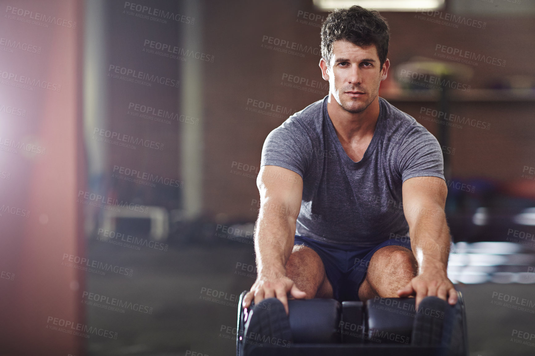 Buy stock photo Shot of a young man doing sit ups in a gym