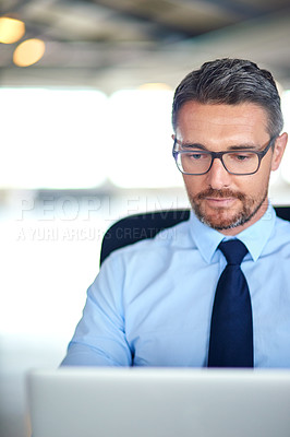 Buy stock photo Shot of a businessman using a laptop in the office