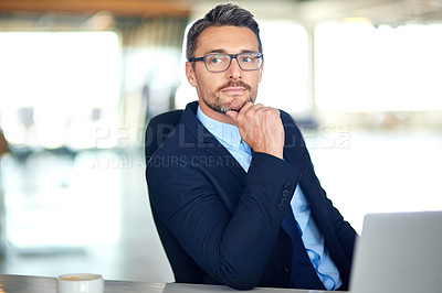Buy stock photo Shot of a thoughtful businessman using a laptop in the office