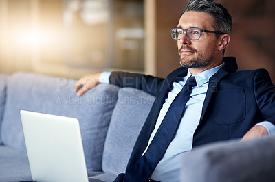 Buy stock photo Shot of a businessman using a laptop on the sofa