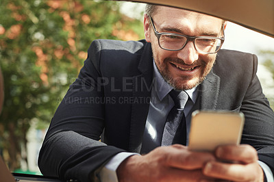 Buy stock photo Shot of a businessman using a phone while leaning against his car