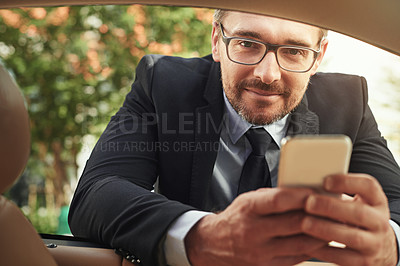 Buy stock photo Shot of a businessman using a phone while leaning against his car