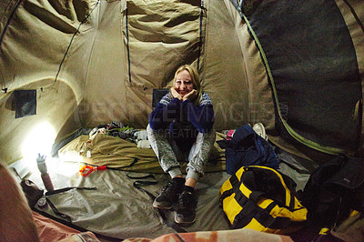 Buy stock photo Shot of a smiling woman sitting inside a tent at night