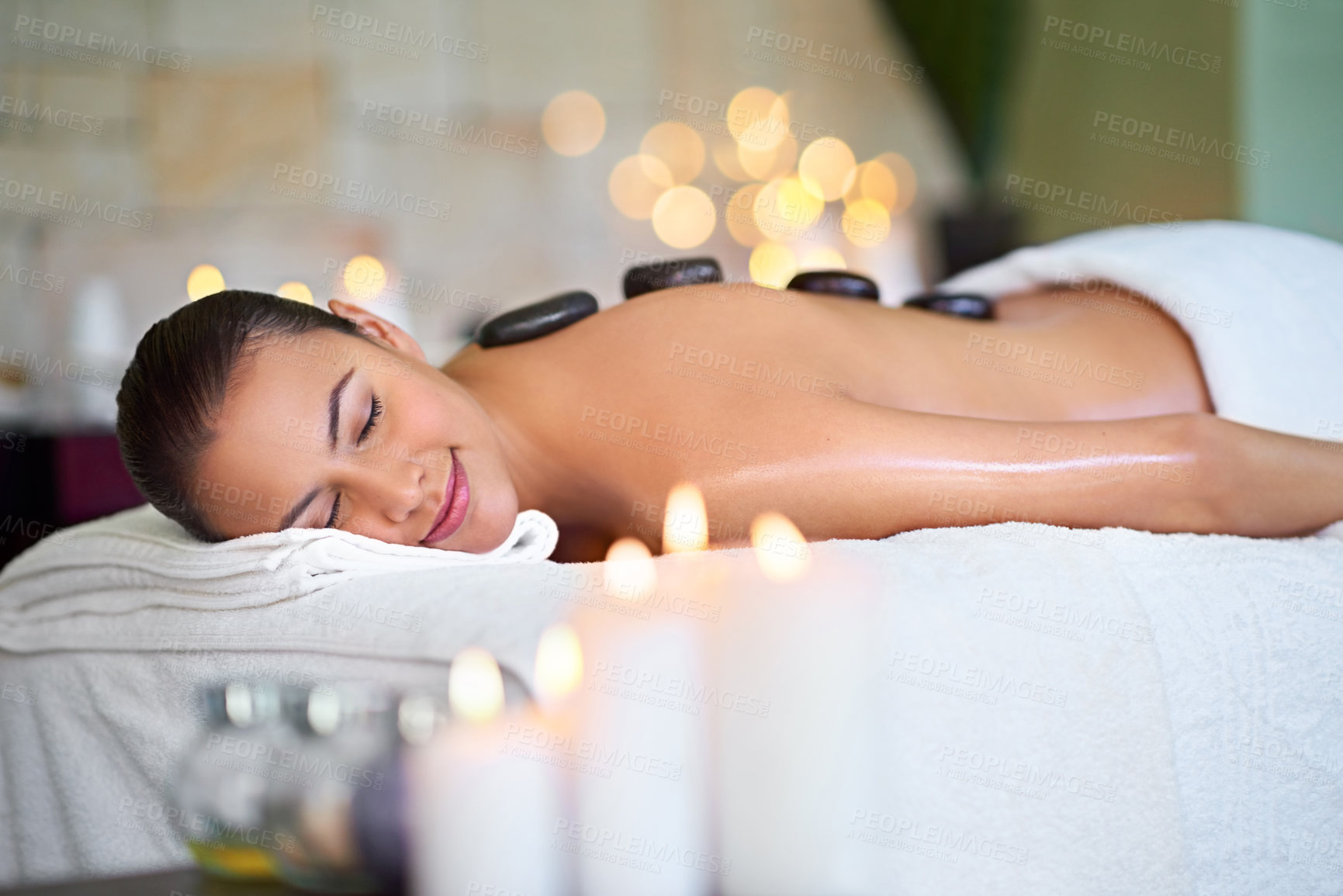 Buy stock photo Shot of a young woman enjoying a hot stone massage at a spa