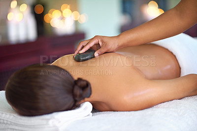 Buy stock photo Relax, woman and hot stone massage with therapist at salon for peace, aromatherapy or stress relief. Hand, masseuse or rocks on back at spa for body treatment, detox and healing for health with bokeh