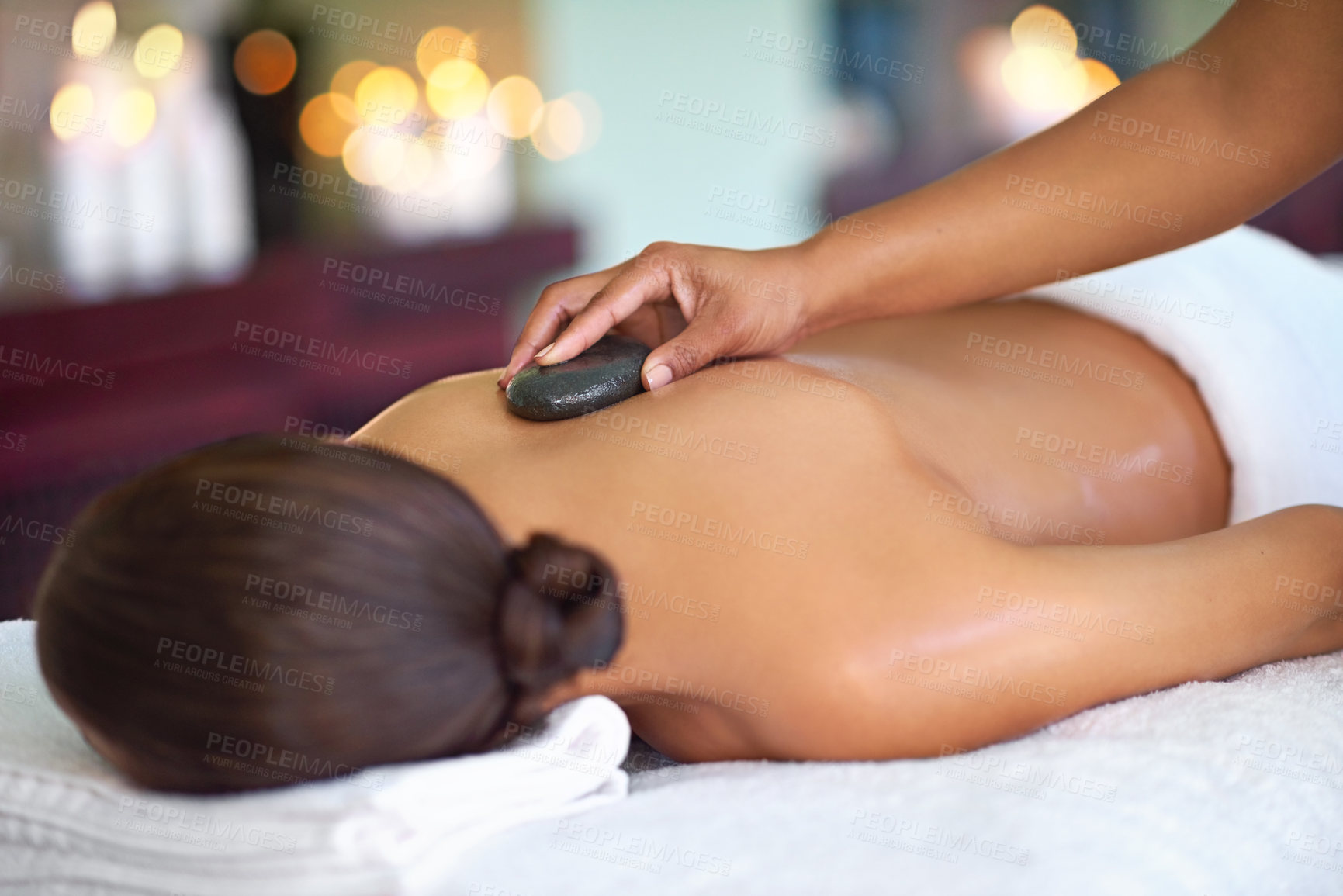 Buy stock photo Relax, woman and hot stone massage with therapist at salon for peace, aromatherapy or stress relief. Hand, masseuse or rocks on back at spa for body treatment, detox and healing for health with bokeh