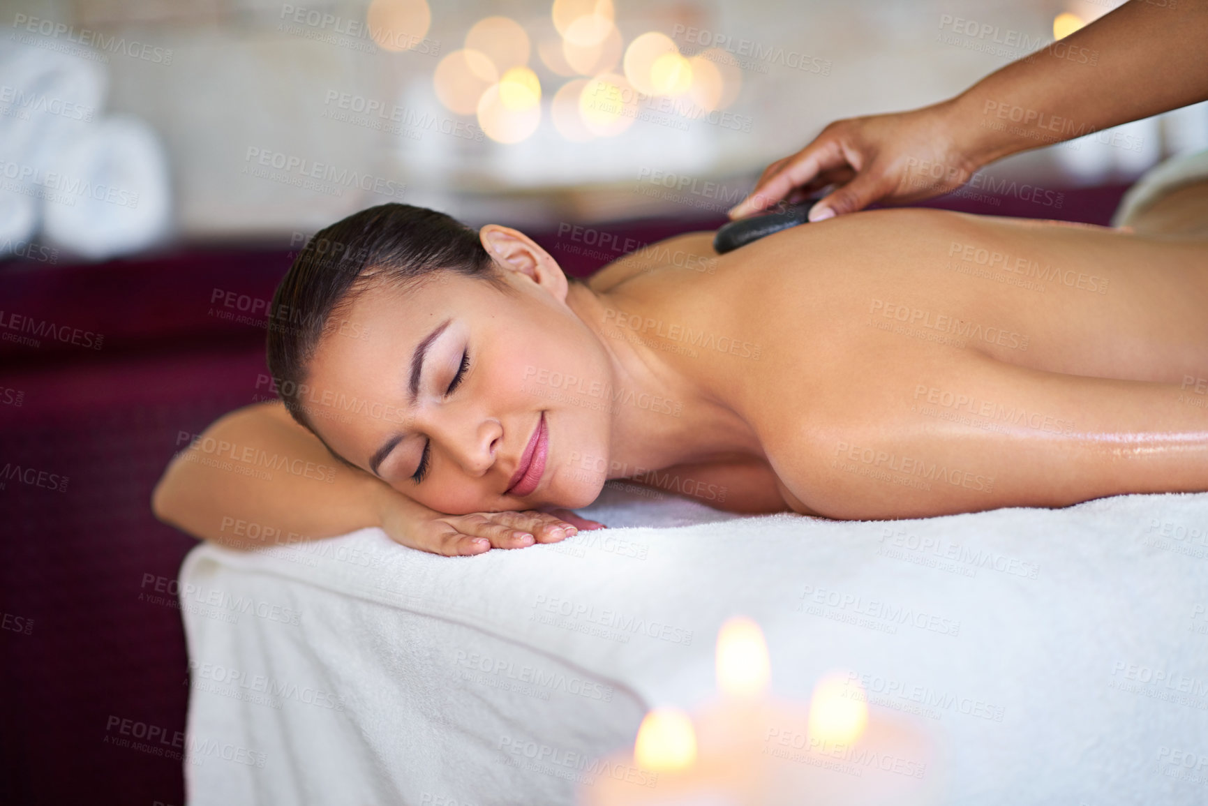 Buy stock photo Calm, woman and hot stone on back for massage with therapist at salon for relax, bokeh and wellness. Hand, masseuse and rocks at spa for body care treatment, health and healing spine for pain relief