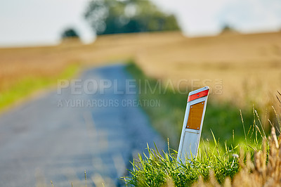 Buy stock photo Closeup of roadside reflector next to a road and green and brown grass. Delineator beside a roadway or street on a summer day. Traffic sign with a blurred background, field or nature