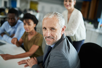 Buy stock photo Portrait of a mature businessman with coworkers sitting in the background