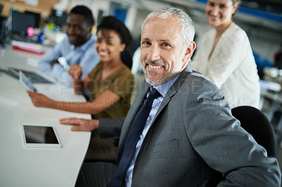 Buy stock photo Portrait of a mature businessman with coworkers sitting in the background