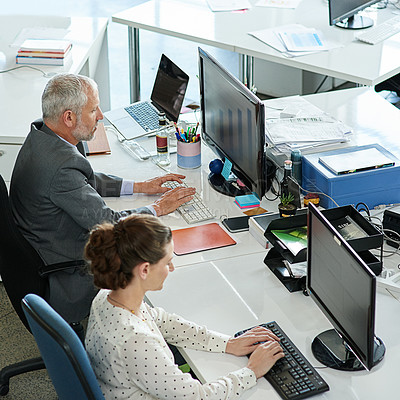 Buy stock photo Shot of colleagues working on their computers while sitting in an office