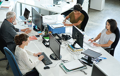 Buy stock photo Shot of a group of coworkers sitting at their workstations in an office