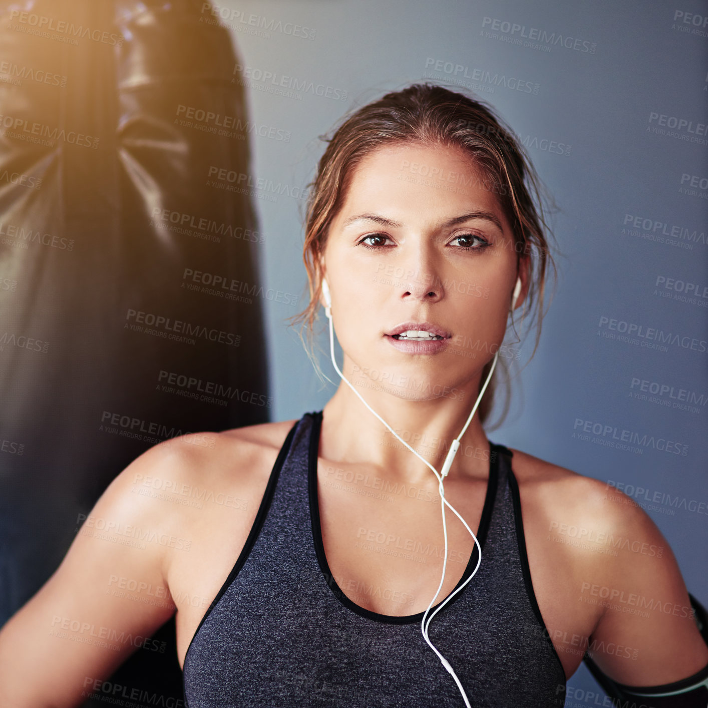 Buy stock photo Portrait, woman and boxer with music, punching bag or exercise for wellness or fitness with grey background. Earphones, athlete and girl in gym, workout or sports with challenge or listen to audio