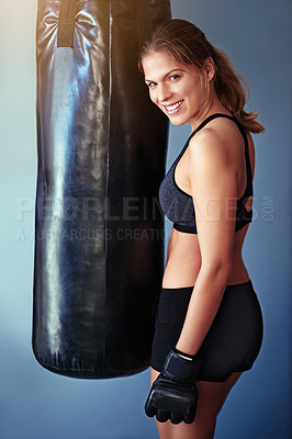 Buy stock photo Portrait of a female boxer standing beside a punching bag