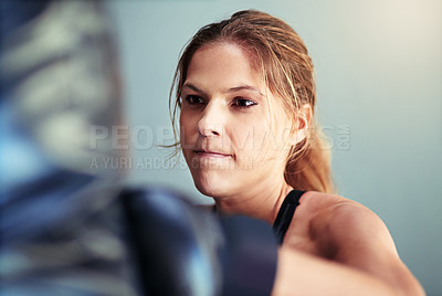 Buy stock photo Shot of a female boxer working out with a punching bag