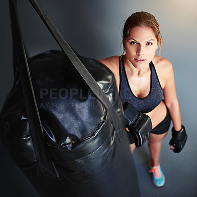 Buy stock photo Portrait of a female boxer leaning against a punching bag
