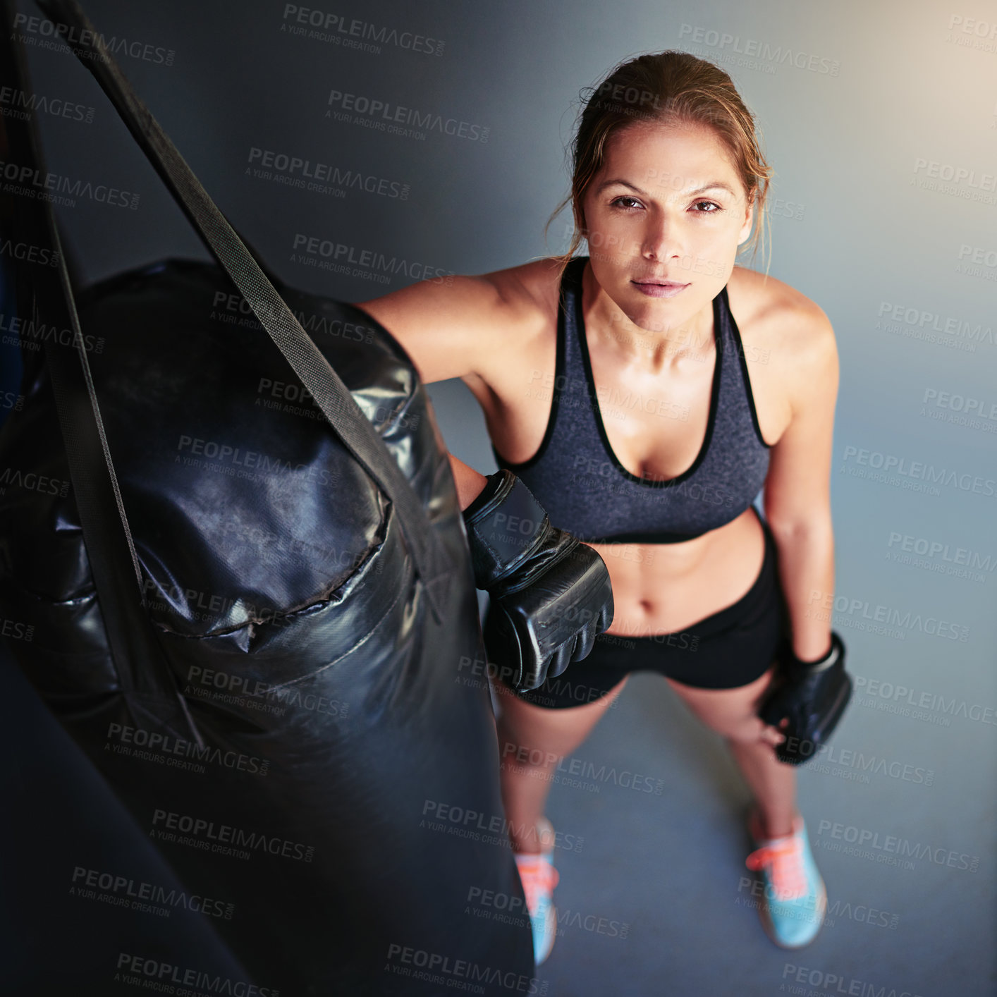 Buy stock photo Portrait of a female boxer leaning against a punching bag