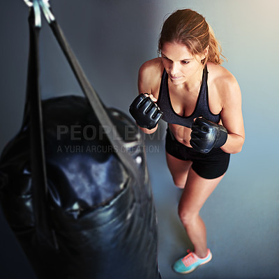 Buy stock photo High angle shot of a female boxer working out with a punching bag