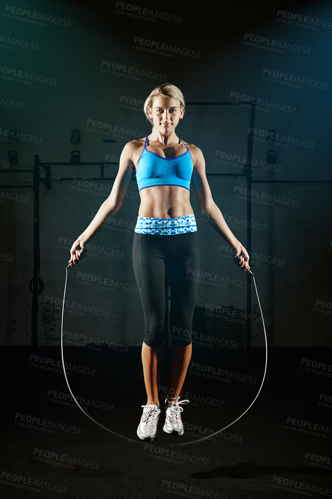 Buy stock photo Shot of a young woman jumping rope in a gym