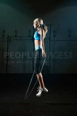 Buy stock photo Shot of a young woman jumping rope in a gym