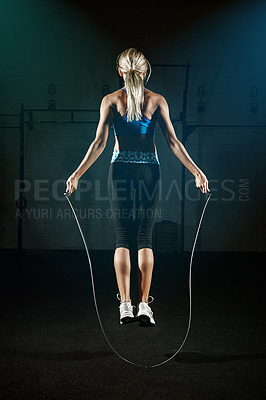 Buy stock photo Shot of a young woman jumping rope in a gym