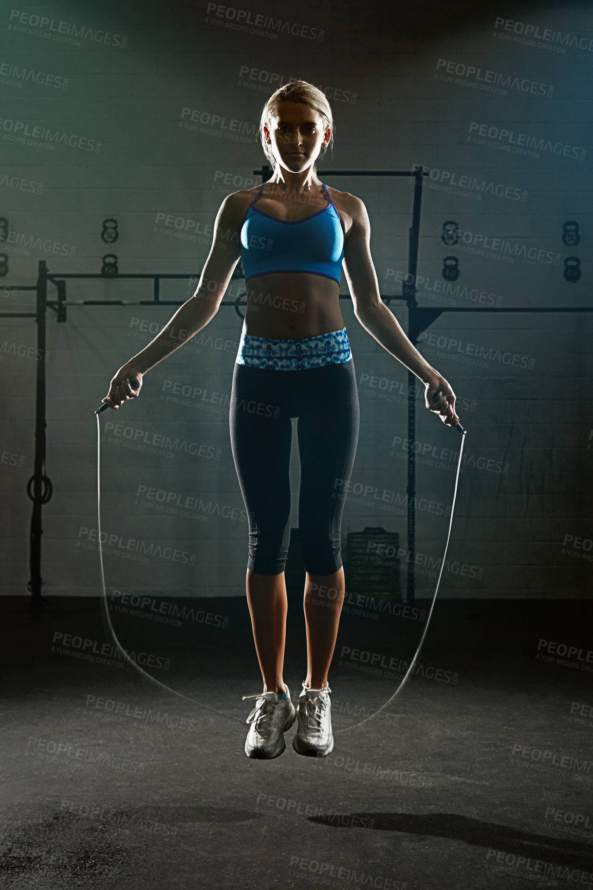 Buy stock photo Shot of a young woman jumping rope in a gym