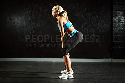 Buy stock photo Shot of a young woman doing kettlebell squats in a gym