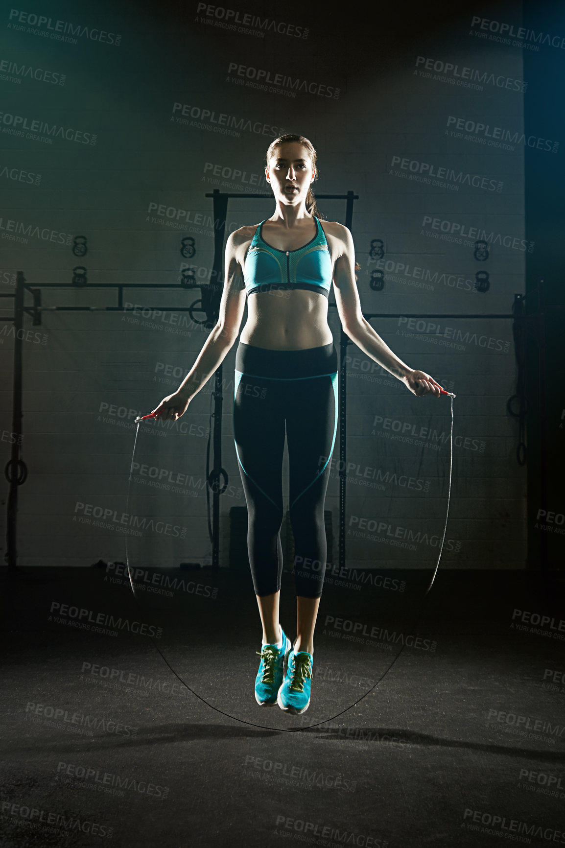 Buy stock photo Shot of a young woman jumping rope in a gym