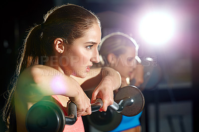 Buy stock photo Shot of two young women working out with weights at the gym