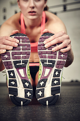 Buy stock photo Cropped shot of a young woman stretching in the gym