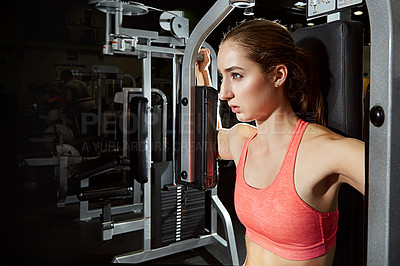 Buy stock photo Shot of a young woman using an exercise machine at the gym