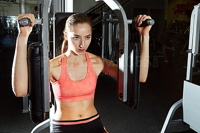 Buy stock photo Shot of a young woman using an exercise machine at the gym