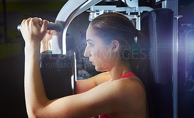 Buy stock photo Shot of a young woman using an exercise machine at the gym