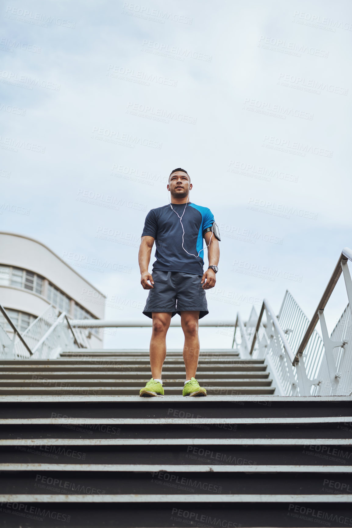 Buy stock photo Low angle shot of a male runner standing on steps in the city