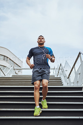 Buy stock photo Fitness, earphones and runner on steps in city with health, wellness and streaming subscription. Urban workout, body care and man listening to music, podcast or app on stairs for morning exercise.