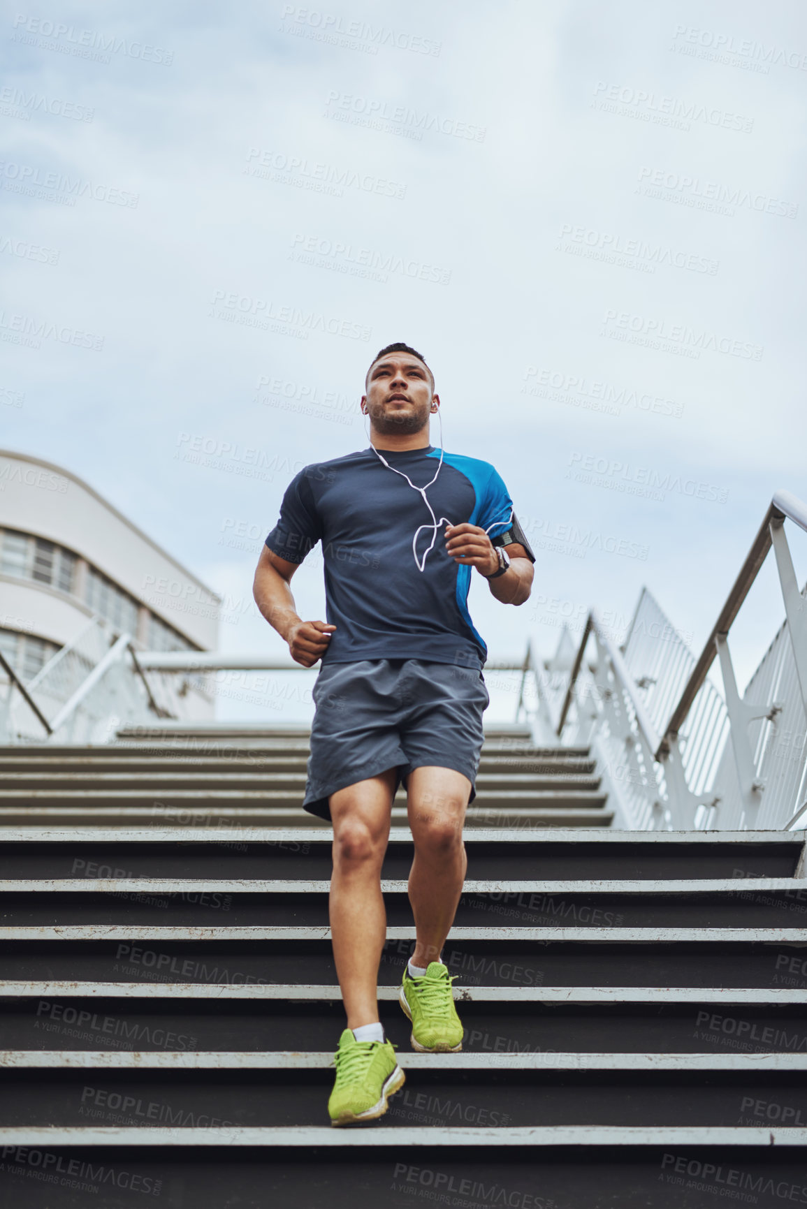 Buy stock photo Fitness, earphones and runner on steps in city with health, wellness and streaming subscription. Urban workout, body care and man listening to music, podcast or app on stairs for morning exercise.