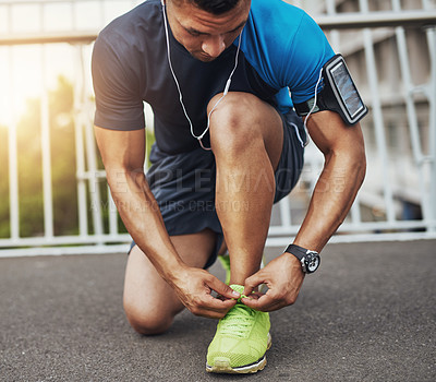 Buy stock photo Shot of a young man tying his shoelaces before a run