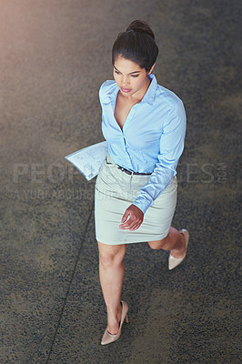 Buy stock photo High angle shot of a confident young businesswoman walking across an office floor