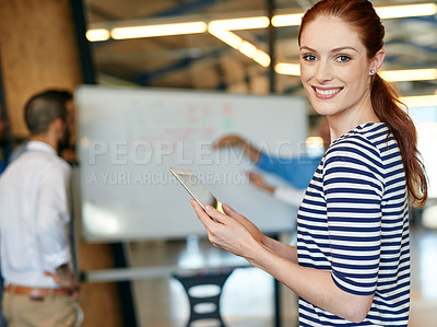 Buy stock photo Shot of a young businesswoman holding a digital tablet with her colleagues in the background