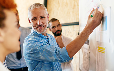 Buy stock photo Shot of a mature businessman explaining something to his colleagues on a whiteboard