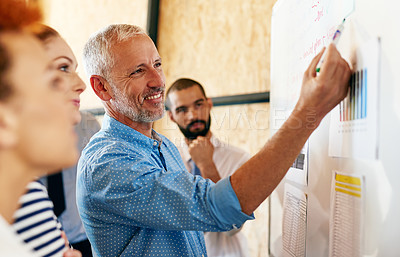 Buy stock photo Shot of a mature businessman explaining something to his colleagues on a whiteboard