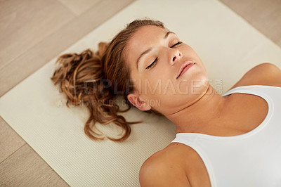 Buy stock photo Cropped shot of a sporty young woman lying on an exercise mat with her eyes closed