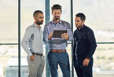 Buy stock photo Cropped shot of three businessmen looking over a tablet in the office