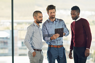 Buy stock photo Cropped shot of three businessmen looking over a tablet in the office