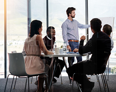 Buy stock photo Shot of a businessman giving a whiteboard presentation to a group of colleagues in a boardroom