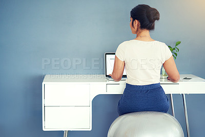 Buy stock photo Rearview shot of a young businesswoman working on her laptop at home
