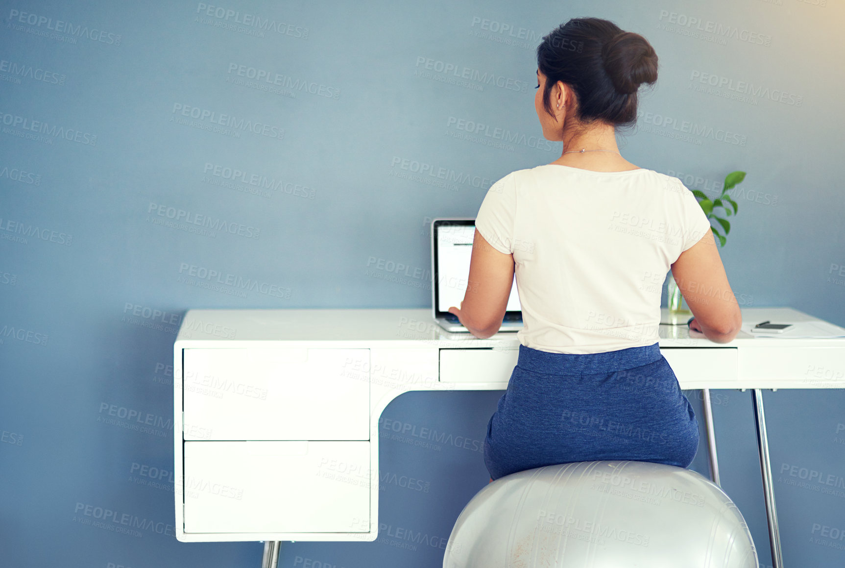 Buy stock photo Rearview shot of a young businesswoman working on her laptop at home