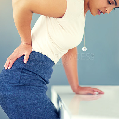 Buy stock photo Cropped shot of a young businesswoman holding her lower back in discomfort